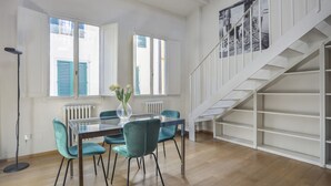 A dining area with a table and chairs, a radiator, a floor lamp, and a staircase. - Florentine Gem Apartment (Firenze)