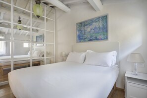 A bedroom with a large bed, a painting on the wall, and a glass partition. - Florentine Gem Apartment (Firenze)
