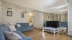 A modern living room with a sofa, television, and a mirrored wall. - Florentine Gem Apartment (Firenze)