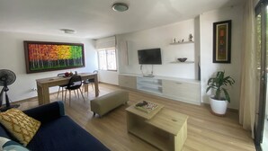 A modern living room with a sofa, coffee table, TV, and artwork. - Apartamento Amplio, Tranquilo , Cómodo y Seguro a 5 min de CC Buenavista, Viva (Barranquilla)