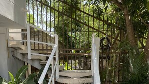 A concrete staircase with white railings leading to a gated area surrounded by lush greenery. - Apartamento Amplio, Tranquilo , Cómodo y Seguro a 5 min de CC Buenavista, Viva (Barranquilla)