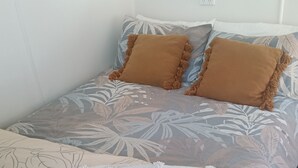 Una cama con una colcha de estampado floral, dos almohadas marrones y una manta blanca.