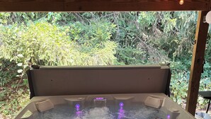 Ein Whirlpool mit Bedienfeld, umgeben von Holzbalken und Grünpflanzen.