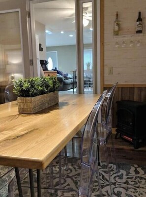 A dining area with a wooden table, clear plastic chairs, a plant, and a fireplace.