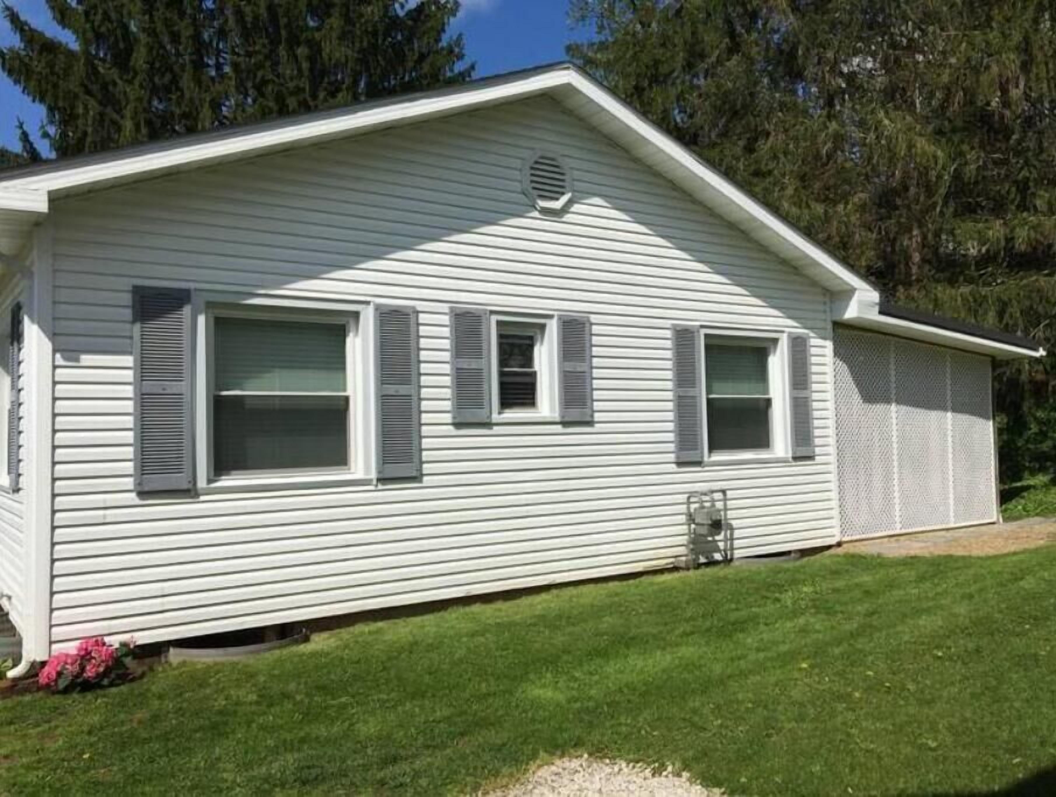 Une maison mobile de plain-pied, dotée d’un toit à deux versants, d’un petit porche et d’un porche d’entrée abrité.