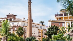 A tall brick chimney, residential buildings with balconies, and lush greenery.