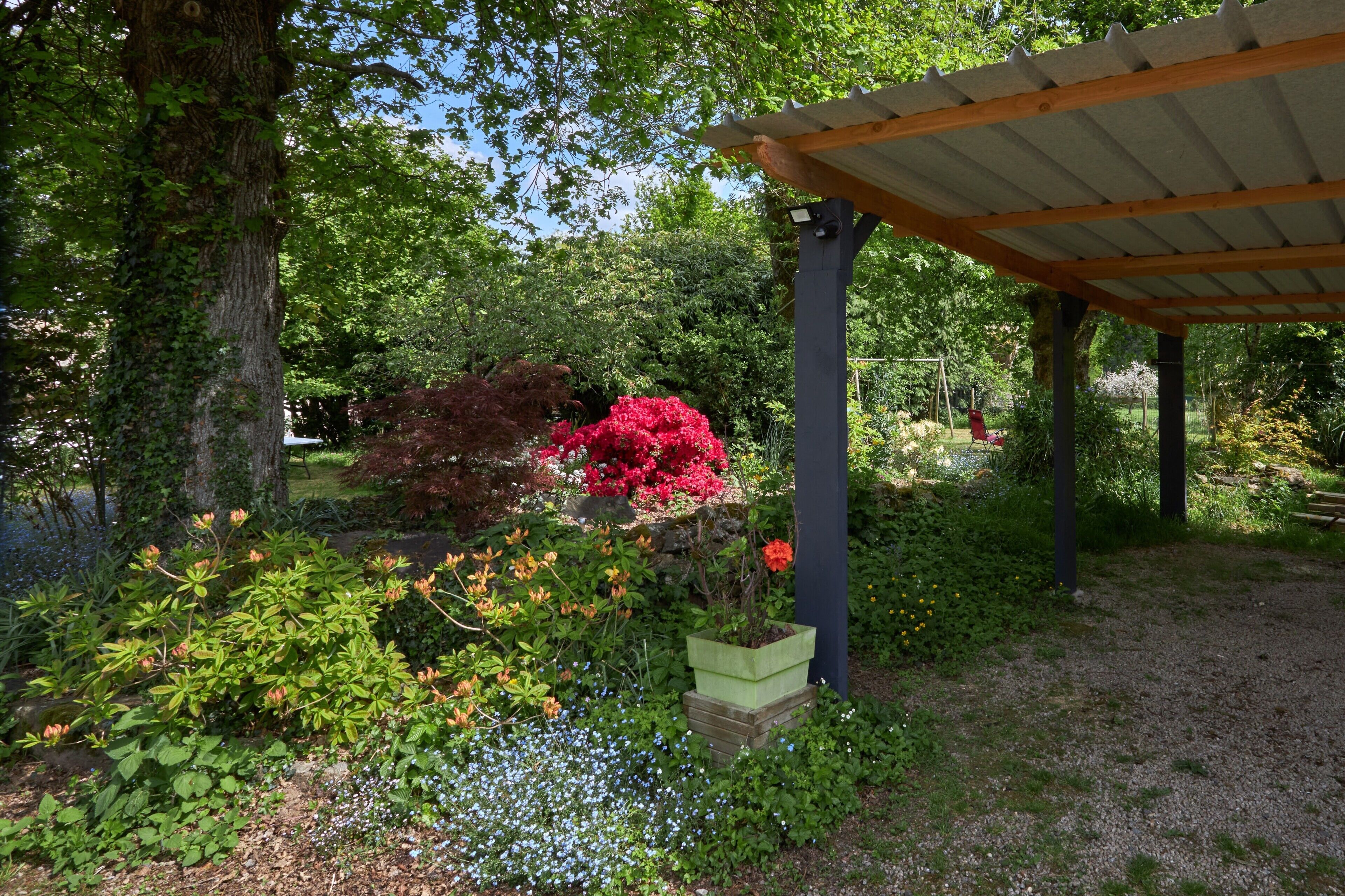 A garden with a pergola, various plants, and a stone planter.