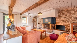 Una sala de estar acogedora con chimenea de piedra, vigas de madera y un televisor moderno.