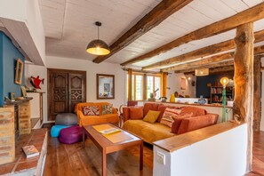 Un intérieur rustique avec des poutres apparentes, un ensemble de canapés, une table basse et une cheminée.