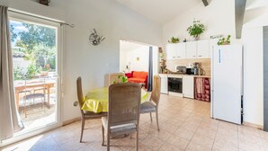 A spacious room with a dining table, chairs, a kitchen area, and a sliding glass door leading to an outdoor patio. - Holiday Home 'Loft Des Cigales' with Private Pool and Private Terrace (Uchaud)