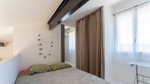 A bedroom with a bed, a desk, and a window with curtains. - Holiday Home 'Loft Des Cigales' with Private Pool and Private Terrace (Uchaud)