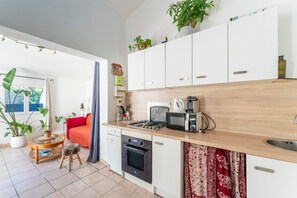 Une cuisine de taille réduite, équipée d’une cuisinière, d’un four à micro-ondes et de placards.