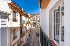 Une rue étroite, bordée de bâtiments des deux côtés, une voiture garée le long de la rue et un ciel bleu dégagé.