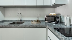 A kitchen with a granite countertop, stainless steel sink, microwave, and built-in oven.