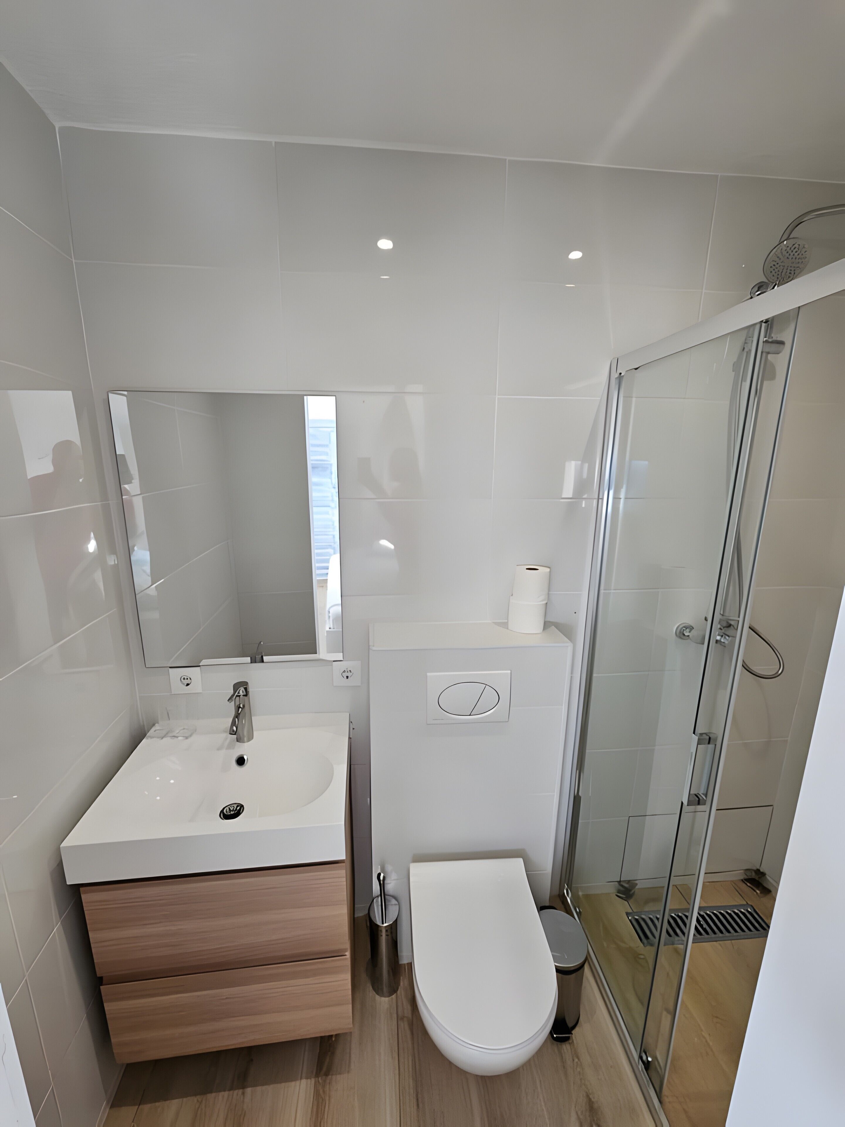 Un baño moderno con lavamanos, espejo, inodoro y cabina de ducha de vidrio.
