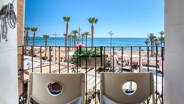 A balcony with chairs, a view of the beach, palm trees, and the ocean. - Apartamento 'Casa amarilla del mar piso 2' con vistas al mar, Wi-Fi y aire acondicionado (La Vila Joiosa)