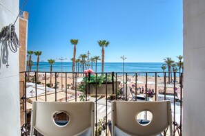 A balcony with chairs, a view of the beach, palm trees, and the ocean. - Apartamento 'Casa amarilla del mar piso 2' con vistas al mar, Wi-Fi y aire acondicionado (La Vila Joiosa)
