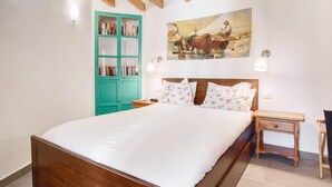 A bedroom with a wooden bed, a green wardrobe, a nightstand, a wall-mounted lamp, and a painting. - Apartamento 'Casa amarilla del mar piso 2' con vistas al mar, Wi-Fi y aire acondicionado (La Vila Joiosa)