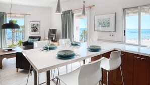 Eine moderne Küche mit einer großen Kochinsel, Essbereich und Blick auf den Strand.