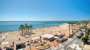 Eine Strandpromenade mit Palmen und Strandbesuchern.