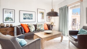 Ein Wohnzimmer mit einer Couch, Sesseln, einem Couchtisch und gerahmten Kunstwerken an der Wand.
