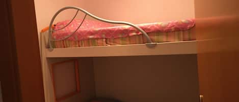 A bunk bed with a pink and striped mattress, a metal frame, and a door with a golden handle.