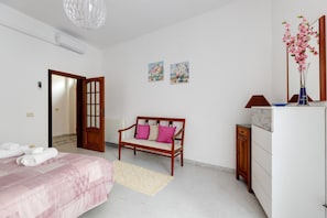 A bedroom with a bed, a wooden bench, a dresser, and a mirror.