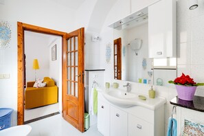 Un baño moderno con un lavamanos grande, un espejo y una planta en maceta.