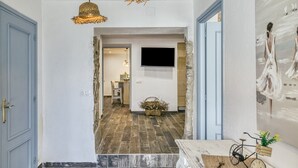 A hallway with a wooden floor, a wall-mounted TV, and a door on the left. - Apartment 'Ca La Maca' with Wi-Fi and Air Conditioning (Llançà)