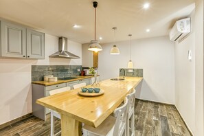 Une cuisine moderne avec un îlot central en bois, des armoires blanches et des luminaires suspendus.
