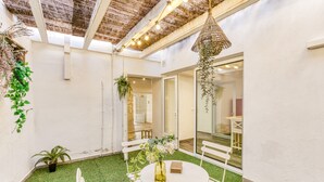 A patio with a round table, white chairs, and a hanging plant. - Apartment 'Ca La Maca' with Wi-Fi and Air Conditioning (Llançà)