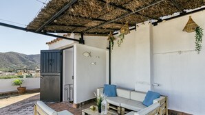 A rooftop patio with a thatched roof, white walls, and a view of the mountains. - Apartment 'Ca La Maca Mediterrani' with Mountain View, Wi-Fi and Air Conditioning (Llançà)