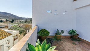 A rooftop terrace with potted plants, a white wall with fish decorations, and a view of distant hills. - Apartment 'Ca La Maca Mediterrani' with Mountain View, Wi-Fi and Air Conditioning (Llançà)