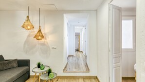 A room with a grey sofa, two hanging wicker lamps, a small round table with a plant, and a wooden floor. - Apartment 'Ca La Maca Mediterrani' with Mountain View, Wi-Fi and Air Conditioning (Llançà)