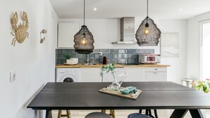 A modern kitchen with a dark dining table, two hanging pendant lights, and a central island with a vase and bowls. - Apartment 'Ca La Maca Mediterrani' with Mountain View, Wi-Fi and Air Conditioning (Llançà)