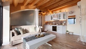 Ein modernes Interieur mit Holzbalkendecke, einer Couch, einem Esstisch und einer Küchenzeile.