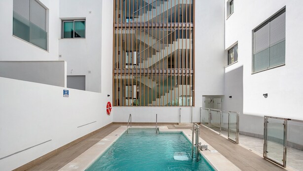 A swimming pool with a glass railing, a fire safety sign, and a staircase leading to an upper level. - Family Apartment 'Coral' with Private Pool, Wi-Fi and Air Conditioning (Conil de la Frontera)