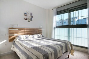 A bedroom with a bed, a window, and wall-mounted light fixtures.