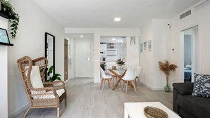 A modern living room with a dining area, a sofa, and a coffee table. - Family Apartment 'Coral' with Private Pool, Wi-Fi and Air Conditioning (Conil de la Frontera)