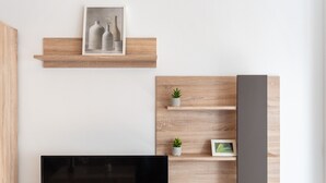 Un salon moderne avec un téléviseur à écran plat, des étagères en bois et un tableau encadré.