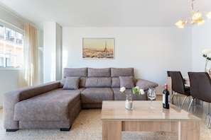 A modern living room with a sectional sofa, a glass coffee table, and a dining area with chairs. - Apartment 'Fuengirola' with Balcony, Wi-Fi and Air Conditioning (Fuengirola)