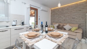 A modern kitchen with a dining area, a sofa, and a brick accent wall.
