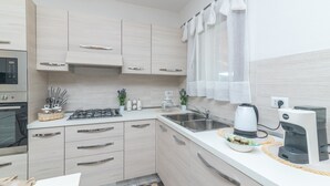 A modern kitchen with a gas stove, sink, coffee maker, and cabinets.