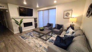 A modern living room with a fireplace, a flat-screen TV, and a sofa set. - Sage Creek Condo E2 - "Amazing Pool & Hot Tubs" (Moab)