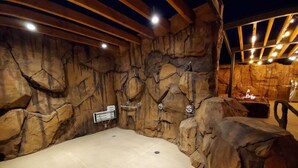 A spa area with a stone wall backdrop, a bathtub, and a wooden ceiling. - Sage Creek Condo E2 - "Amazing Pool & Hot Tubs" (Moab)