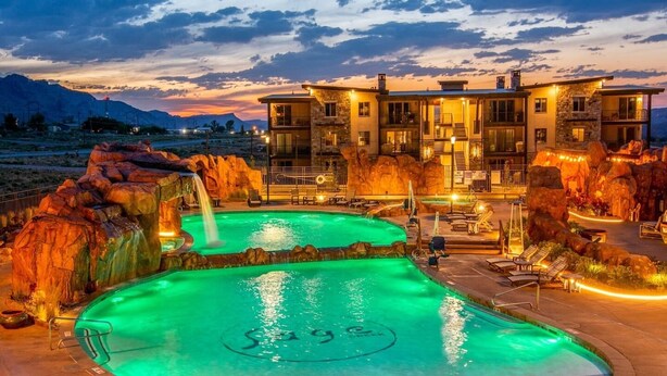 A resort with a large outdoor swimming pool, a waterfall feature, and a multi-story building with balconies. - Sage Creek Condo E2 - "Amazing Pool & Hot Tubs" (Moab)