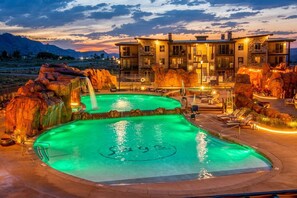 Un complexe hôtelier doté d’une grande piscine extérieure, d’une cascade et d’un bâtiment à plusieurs étages avec des balcons.