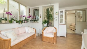 Un salón con un sofá y un sillón de mimbre, y una planta en maceta.