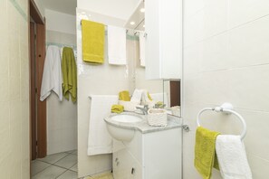 Een badkamer met een wastafel, spiegel en handdoekhouder.