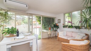 Un comedor con una mesa dispuesta para dos, un sofá de mimbre y una planta en maceta.